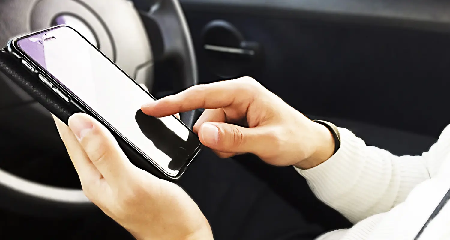 車でスマホを触る男性の画像